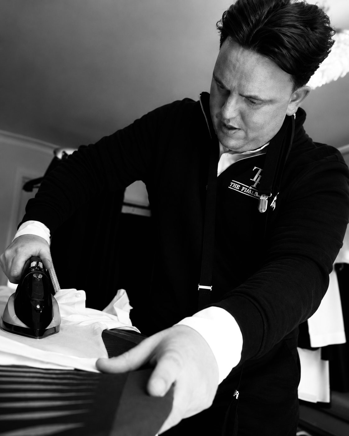 Raymond pressing a shirt with an iron before the wedding party gets dressed.