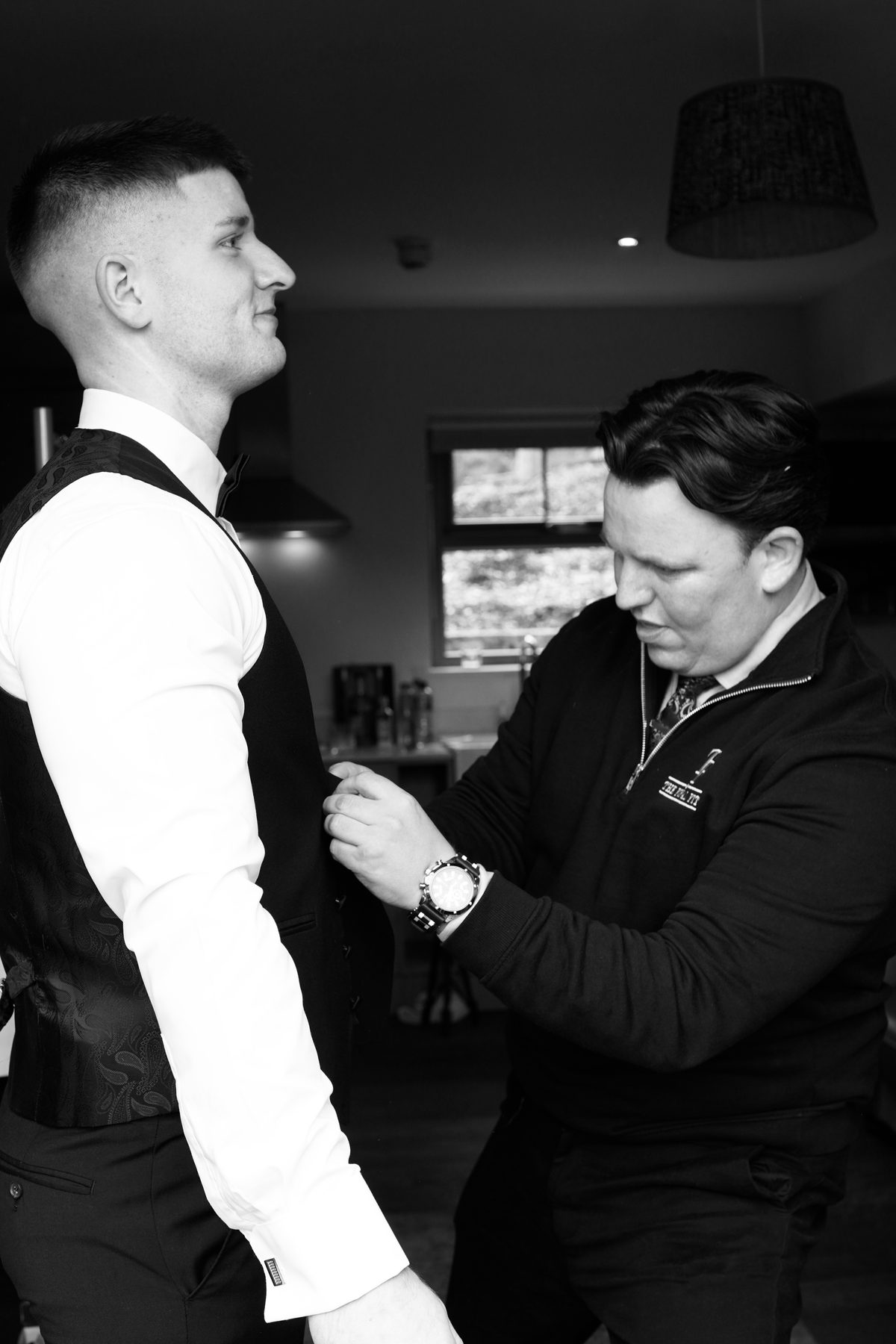 Raymond adjusting the front of a groomsman’s waistcoat.